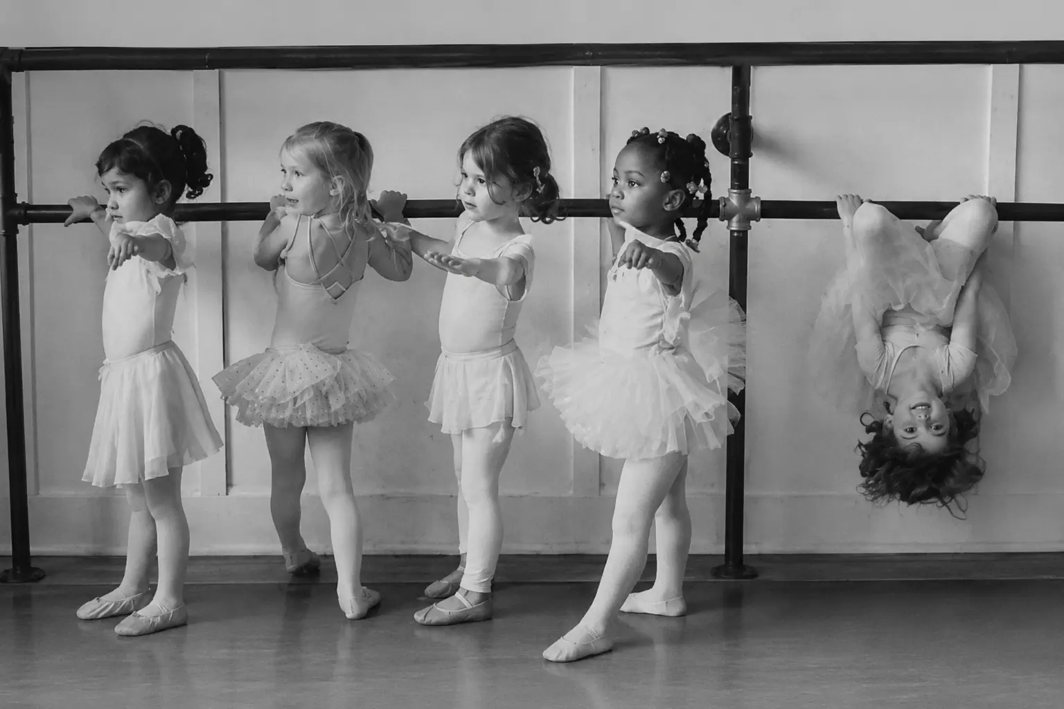 Children practicing ballet at a barre while one child hangs upside down, illustrating how brands can stand out by breaking from competitors.